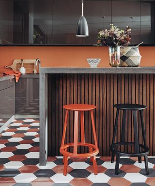 A kitchen with hexagonal kitchen floor tile ideas in white, burnt orange and black.