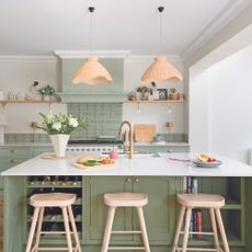 Green kitchen with island and brass tap