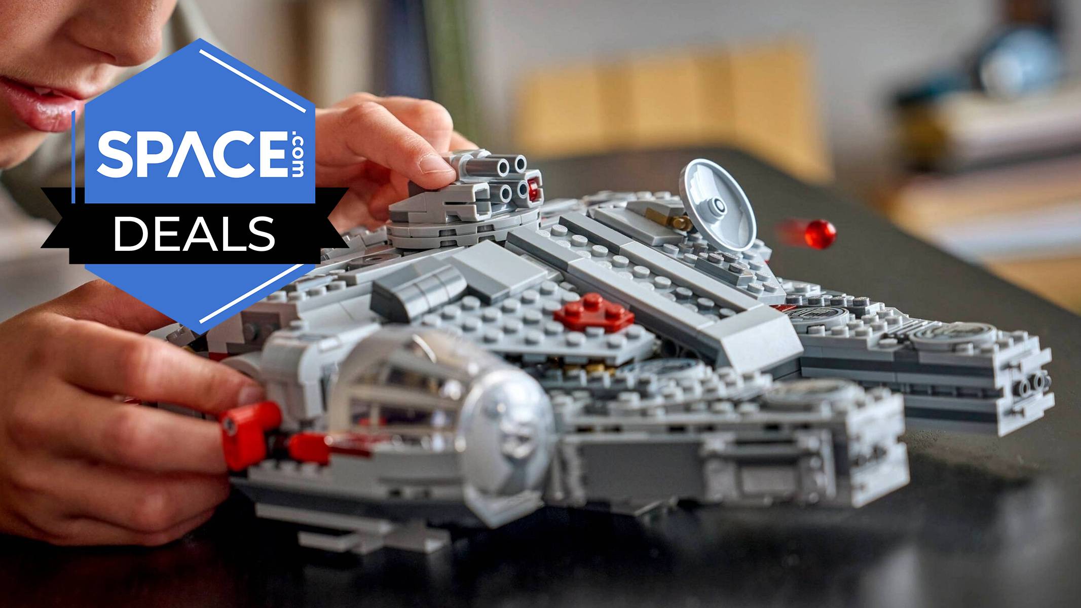 A child holding and playing with a Lego Star Wars Smart Play Millennium Falcon, the ship resting on the table. 