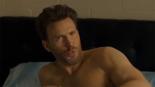 Chris Evans shirtless in bed in Honey Don't! staring at the camera.