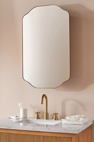Pink bathroom with mirror and sink featuring bronze faucet