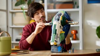 A man moving the wings of the Lego Jango Fett's Firespray-Class Starship model