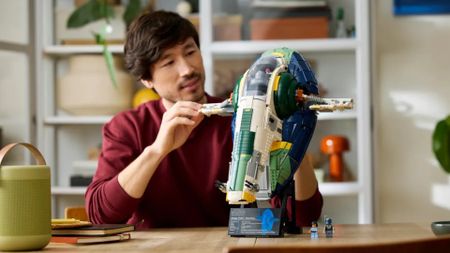 A man moving the wings of the Lego Jango Fett's Firespray-Class Starship model