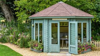 pale blue hexagonal summer house in country garden