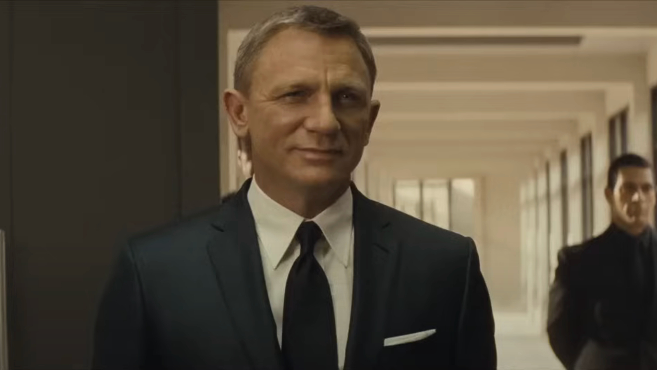 Daniel Craig stands smiling defiantly in Spectre.