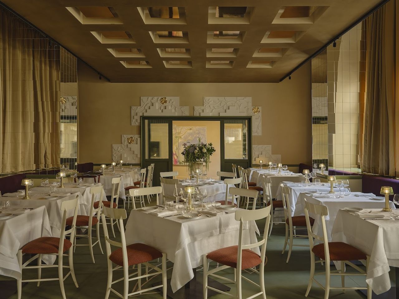 A 1960s-inpired restaurant features a pastel-hued color palette, vintage-style furniture, and mirrored disco-like ceilings as well as wall reliefs.
