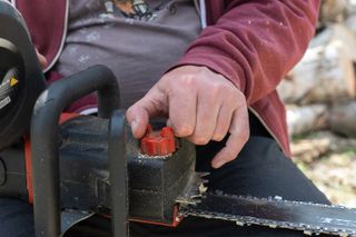 Man using a tensioner on a chainsaw