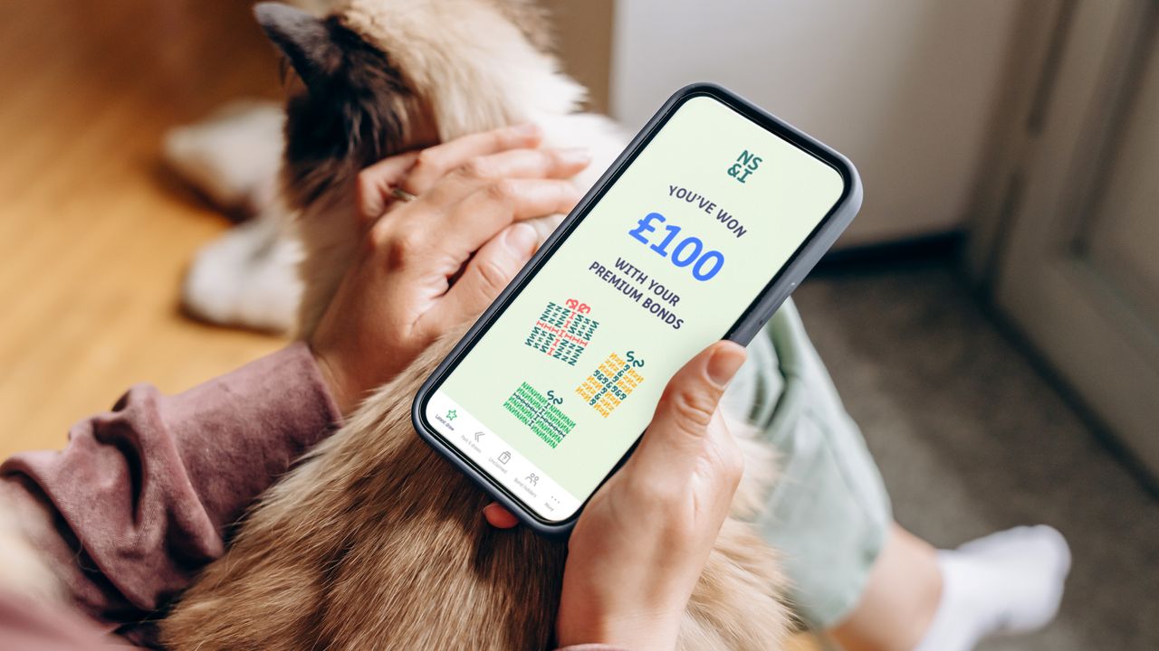 Person holding smartphone with NS&amp;I app saying &#039;you&#039;ve won&#039;