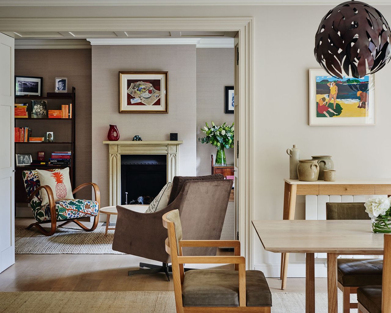 A view into a living room with a fireplace and two armchairs from a dining area