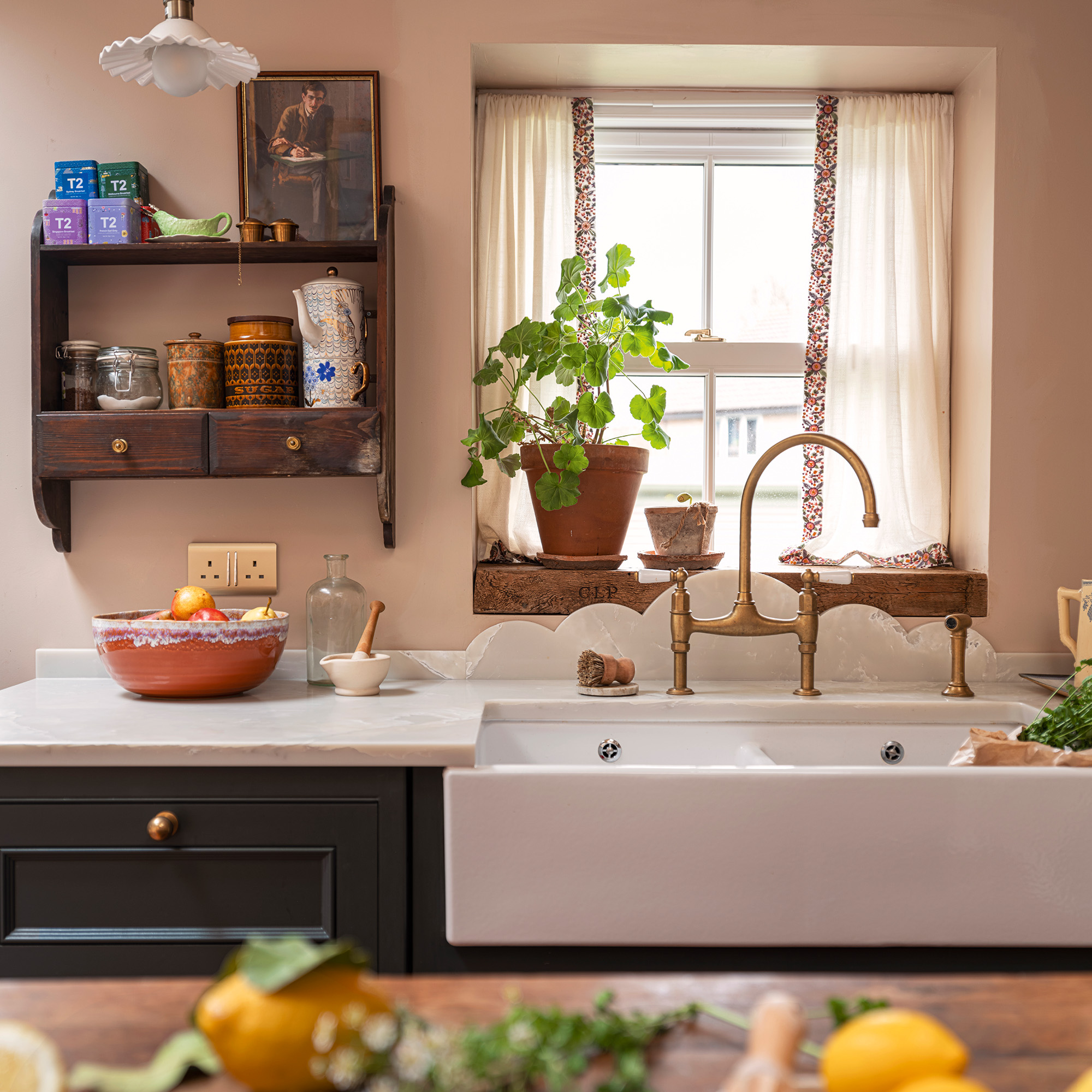 butler sink in country kitchen with pink walls and green cabinetry vintage shelving