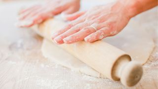 A person using a rolling pin to roll out pastry