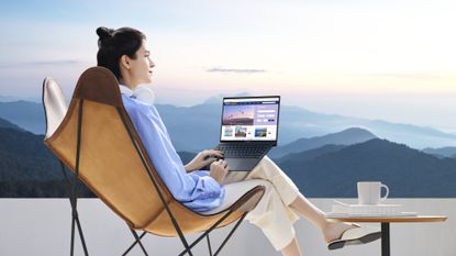The Asus Zenbook S13 OLED in use on a balcony, overlooking some mountains