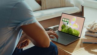 Dell XPS 13 9350 open on a desk with a person navigating the cursor with its touchpad