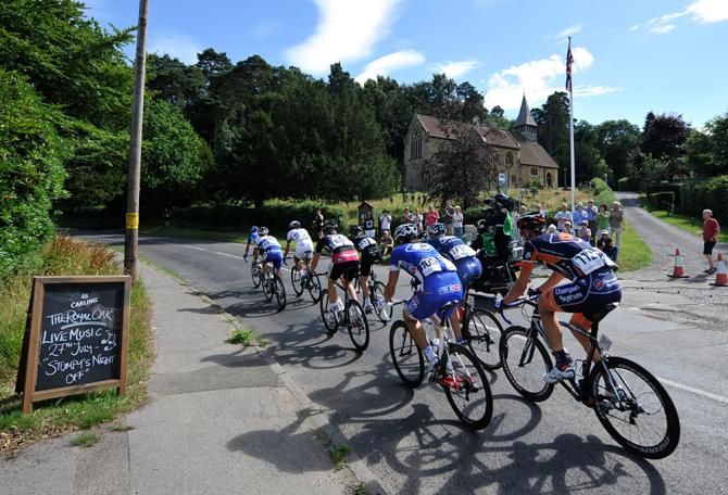 The peloton rides past a church in the Surrey countryside.