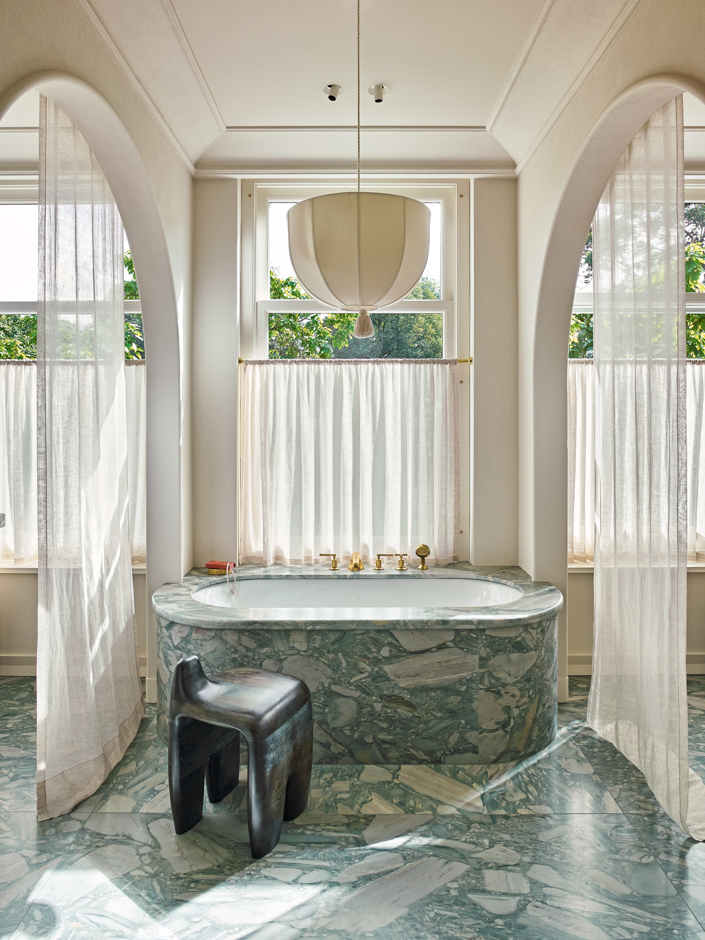 Bathroom with blue marble floor and bathtub, curtains to separate areas, and white linen light