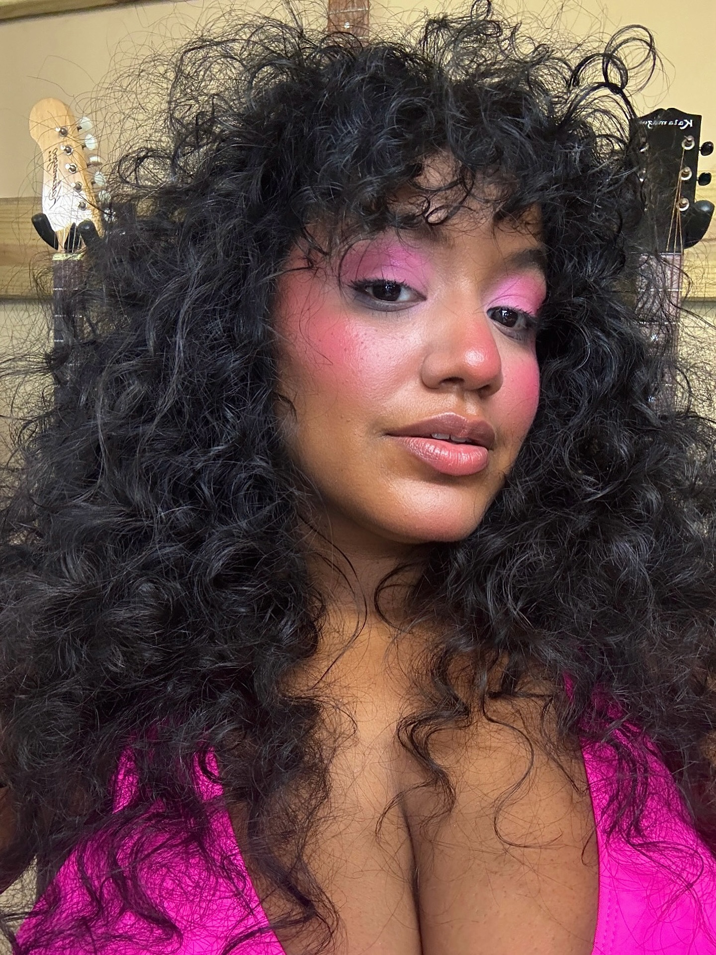 A woman with a wolf cut wearing pink eye shadow and blush.