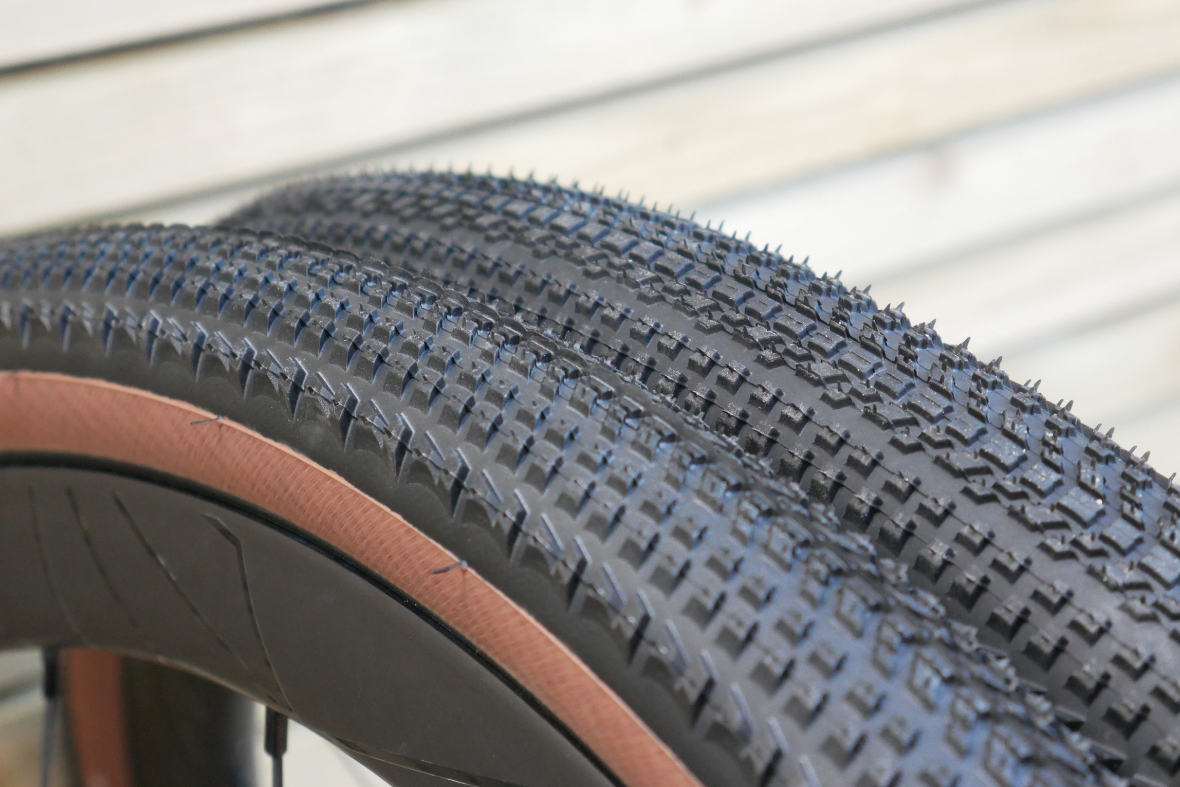 A close-up of the Hutchinson Touareg Race 45mm directional tread profile with both tyres side by side against a wooden cladding background