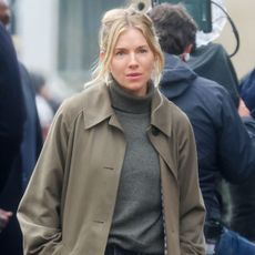Sienna miller wears a sezane clyde trench coat and gray turtleneck sweater.