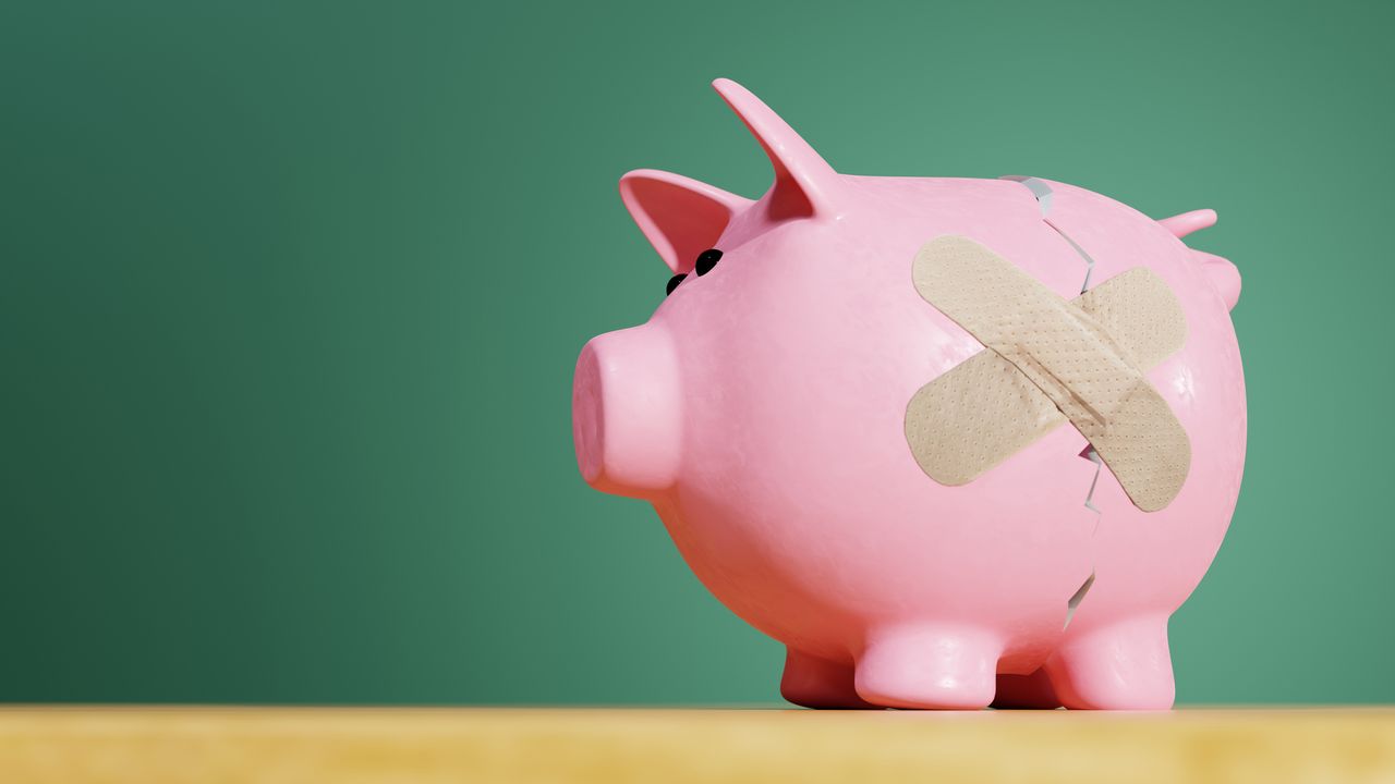 Pink piggy bank with a crack covered by a band-aid