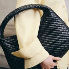 Woman holding Selfridges bag and wearing yellow shirt