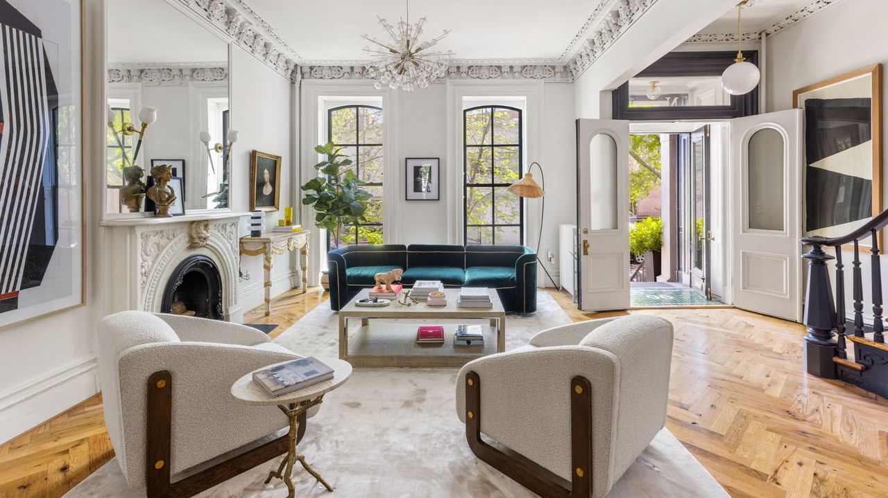 living room with fireplace, white armchairs and green sofa, and chandelier