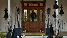 Front porch area decorated with gothic Halloween lights, including twinkling willow trees, witches, lanterns, and an all-black wreath.