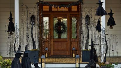 Front porch area decorated with gothic Halloween lights, including twinkling willow trees, witches, lanterns, and an all-black wreath.