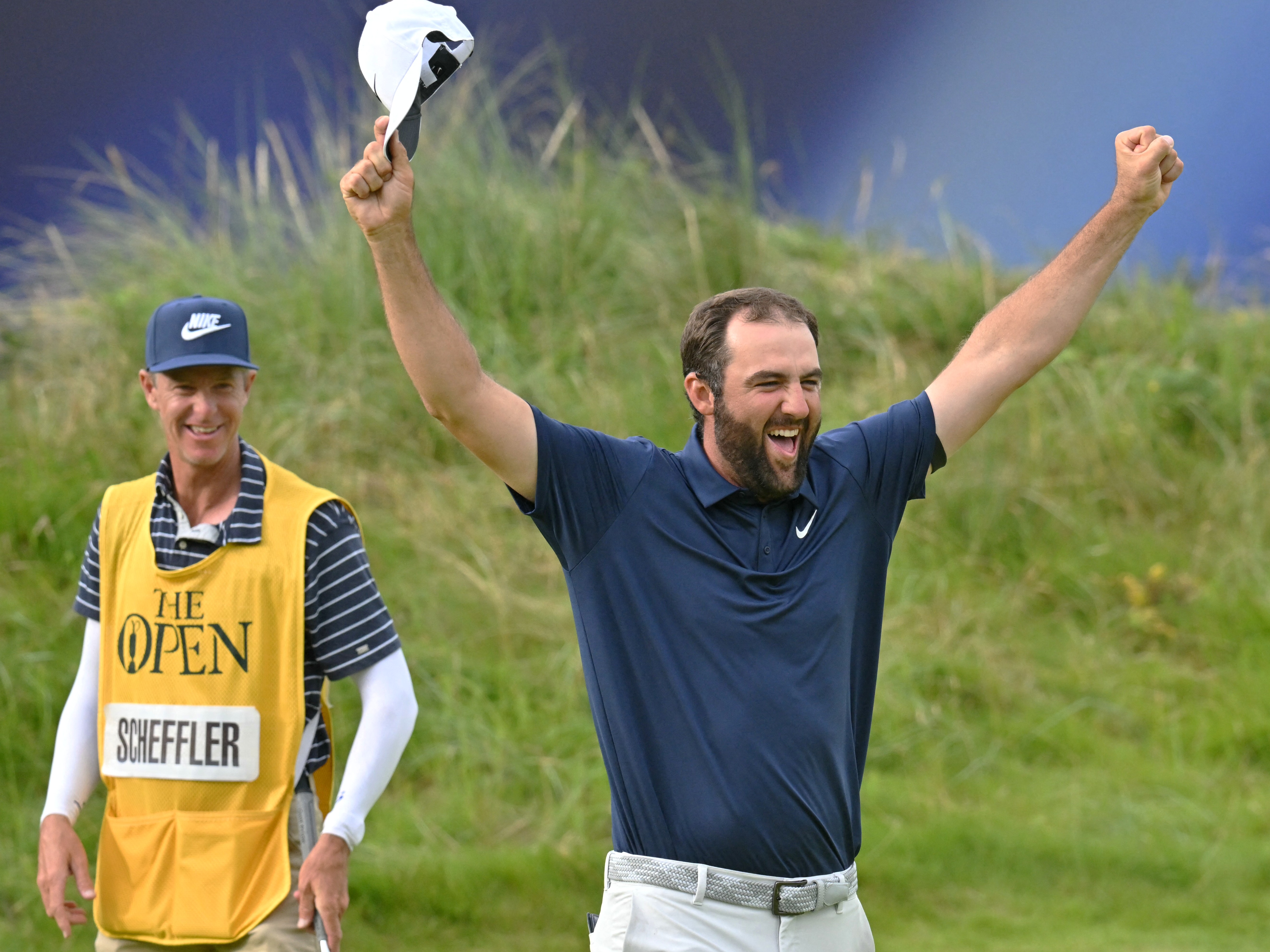 Scottie Scheffler and his caddie Ted Scott celebrate on the 18th green after his victory in the 153rd Open Championship at Royal Portrush in 2025