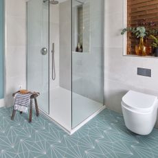 blue and white geometric floor tiling, floating toilet and walk in shower