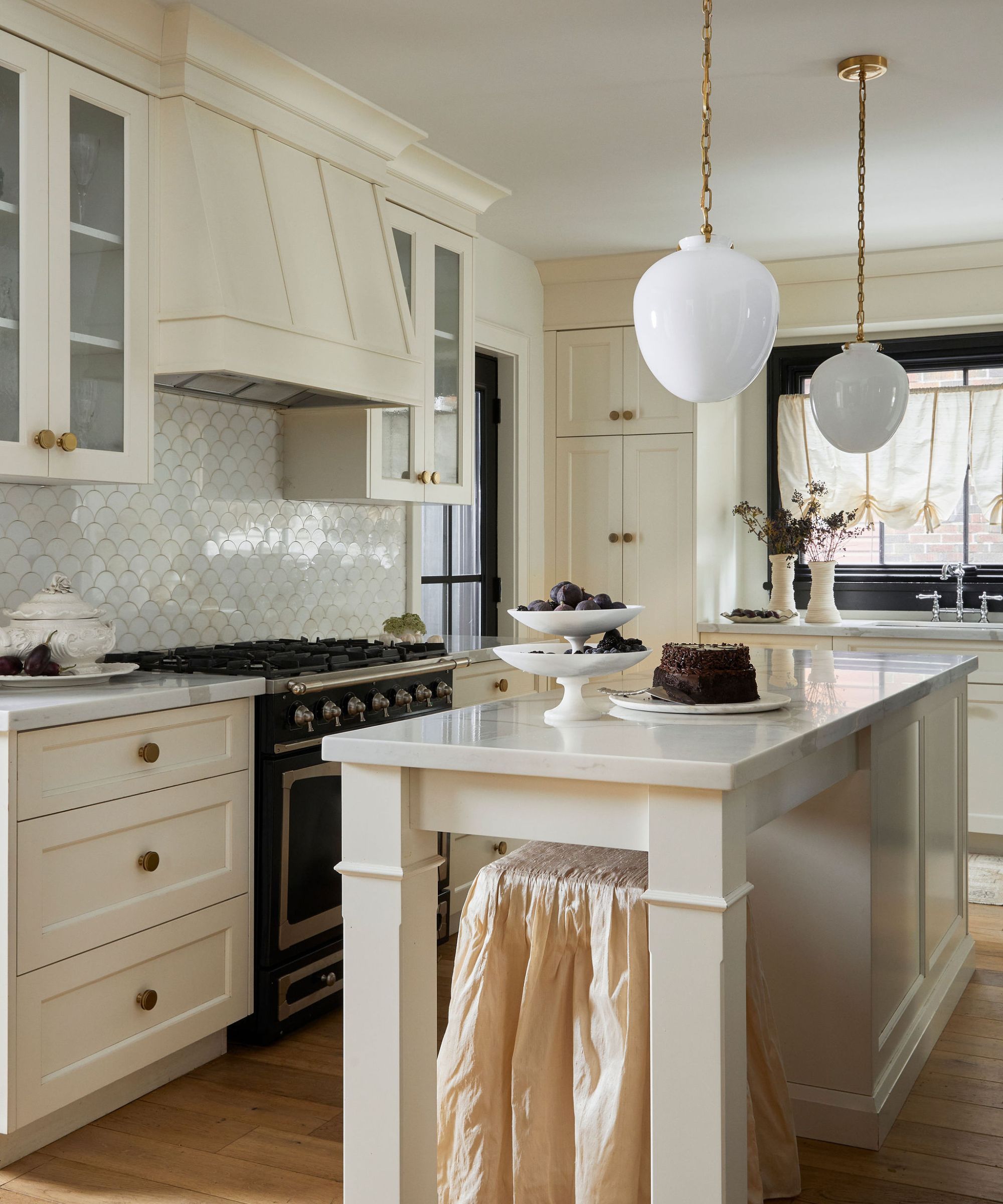 Cream kitchen with a narrow island and two glass pendants hanging above
