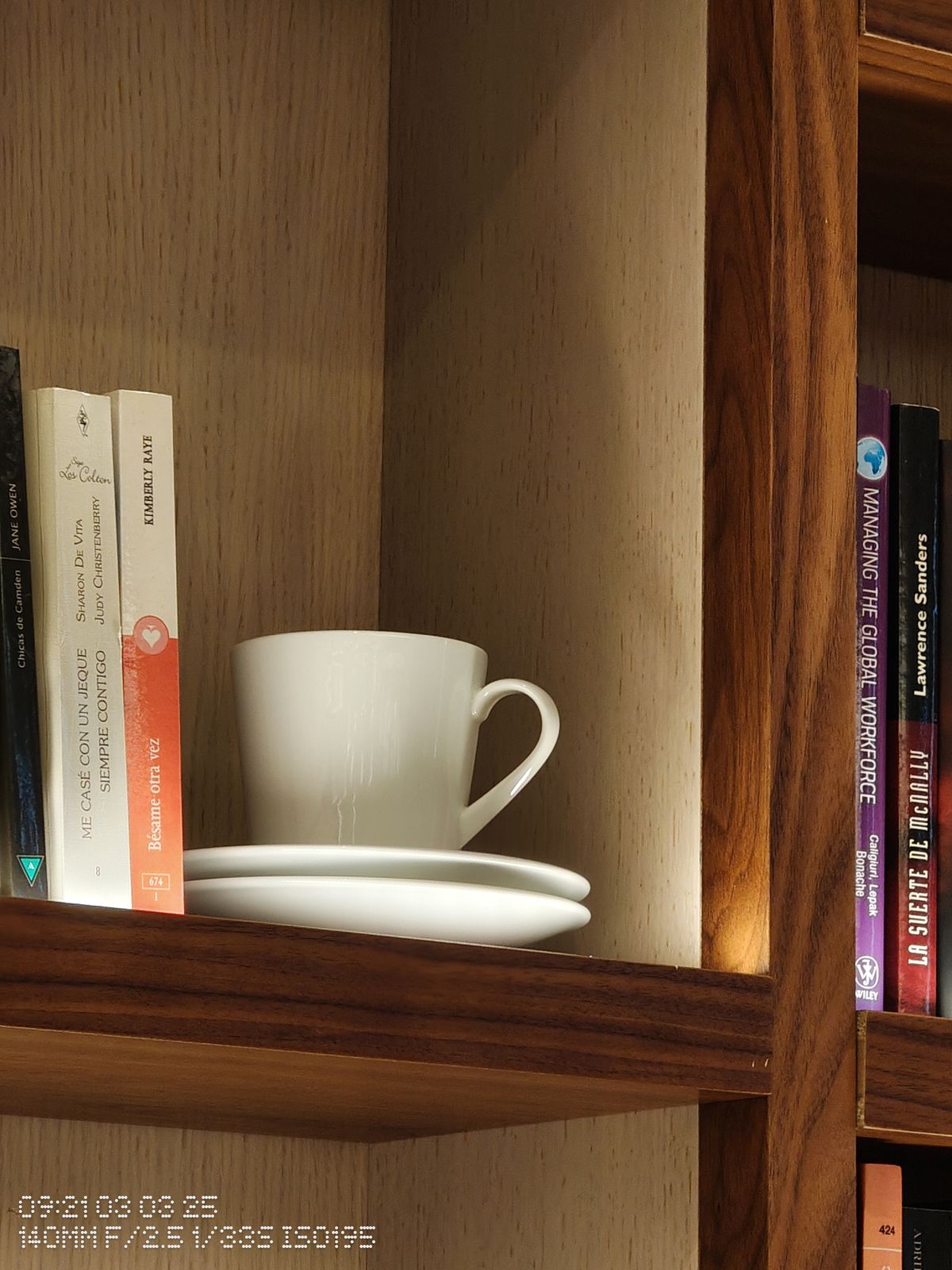 A coffee mug next to some books on a shelf
