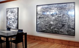 Framed black and white maps on wall with black table and chairs in front