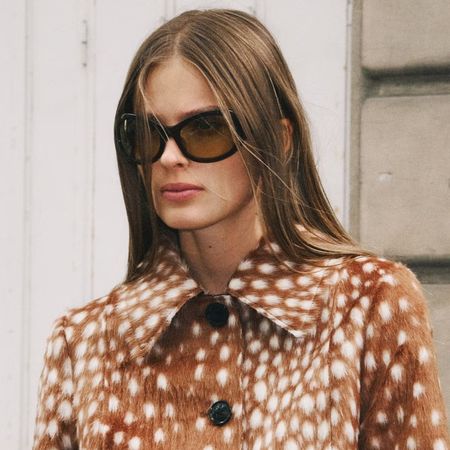 A Mango model wearing a deer-printed coat and oval sunglasses