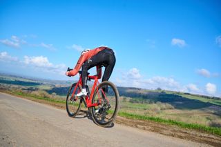 Cyclist in an aero tuck on a red road bike