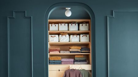 Dark blue paneled walls showing an alcove opening with shelves of neatly folded clothing and drawers