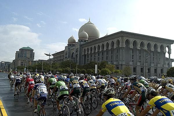The peloton pass a Malaysian Government building near the startline in Putrajaya.