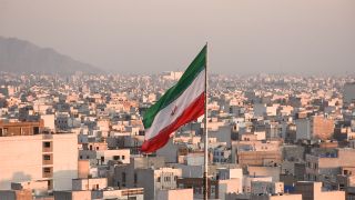 Flag of Iran flying above a city skyline
