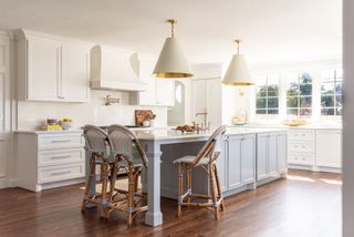 traditional kitchen with pale gray island with dining area and large pendant lights