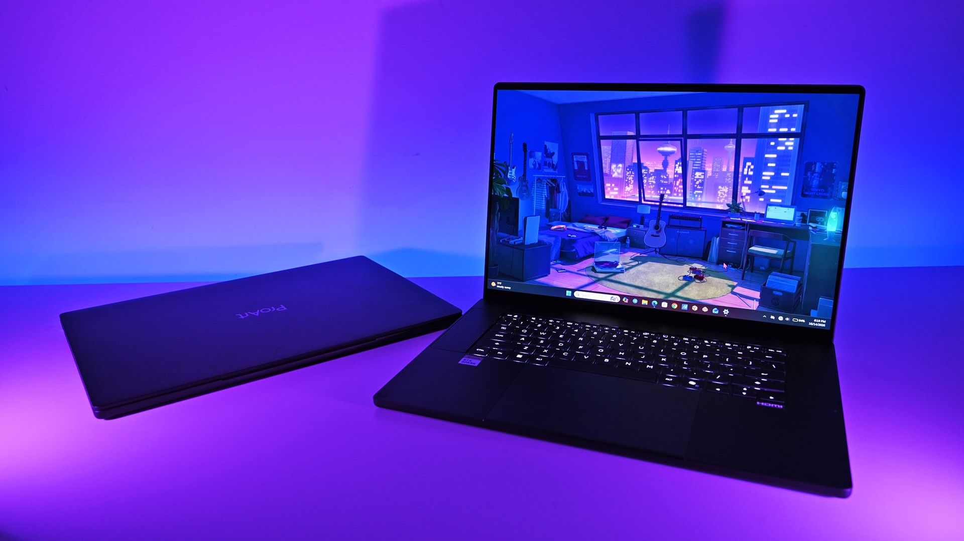 Two ASUS ProArt P16 laptops under purple lighting: one closed showing the ProArt logo lid, and one open displaying an illustrated desktop background.