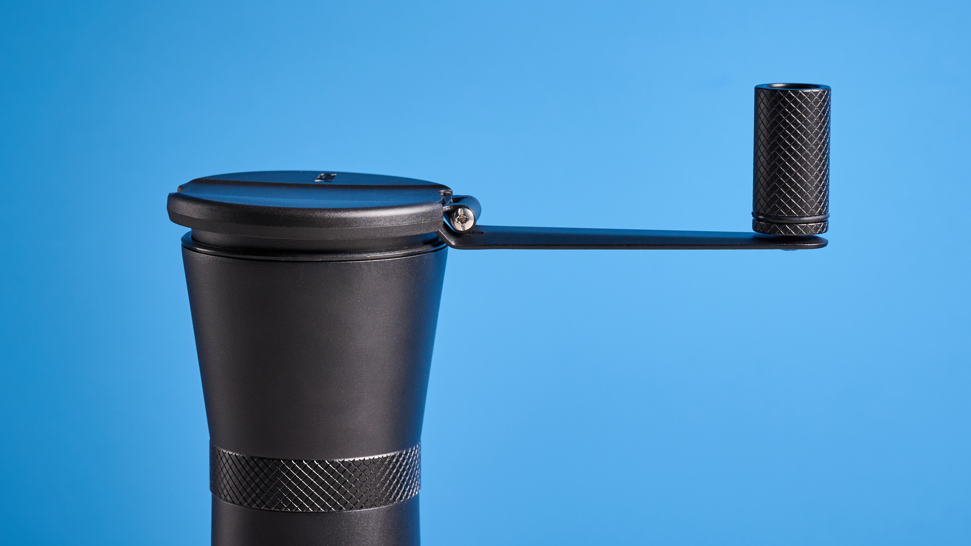 MiiR New Standard Hand Grinder in matte black photographed in front of a blue background