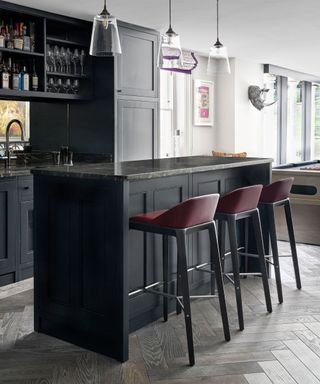 Bar area in an open plan kitchen dining area, black painted island with bar stools.