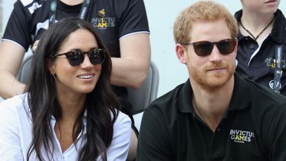 Prince Harry and Meghan Markle wearing sunglasses sitting at the 2017 Invictus Games