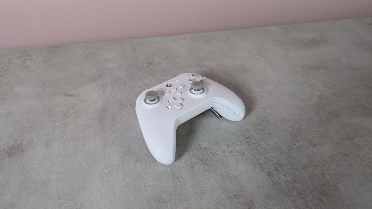 Three-quarter view of GuliKit KK3 Max, on a desk with pink wall in background