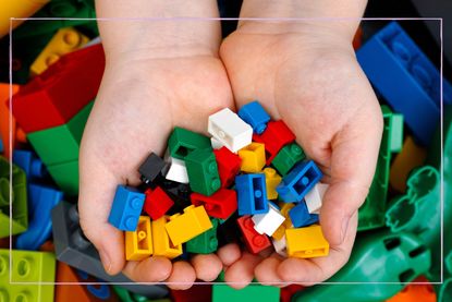 A close up of a person holding LEGO blocks in their hands