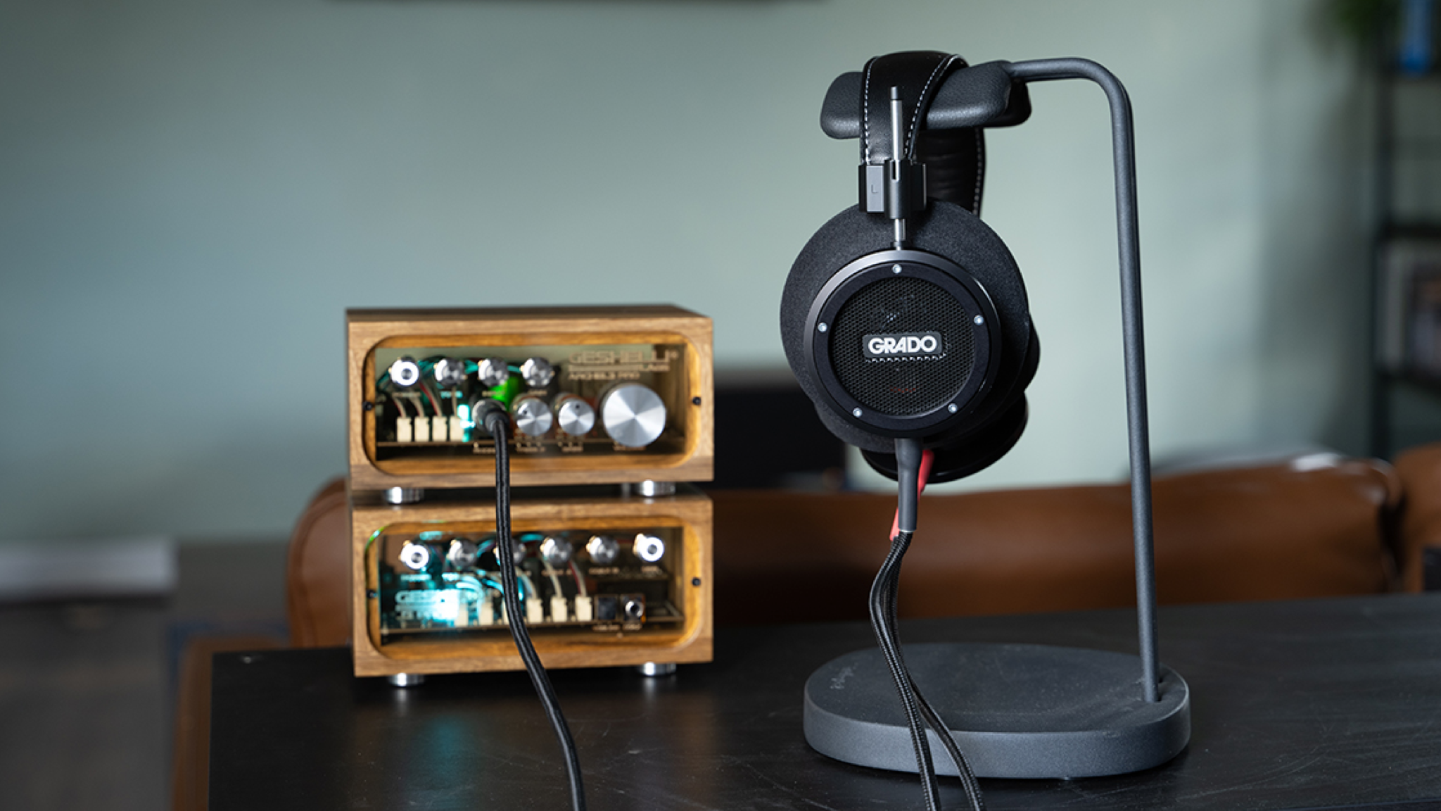 The Grado Signature S750 headphones on a stand next to a wooden-framed headphone amplifier