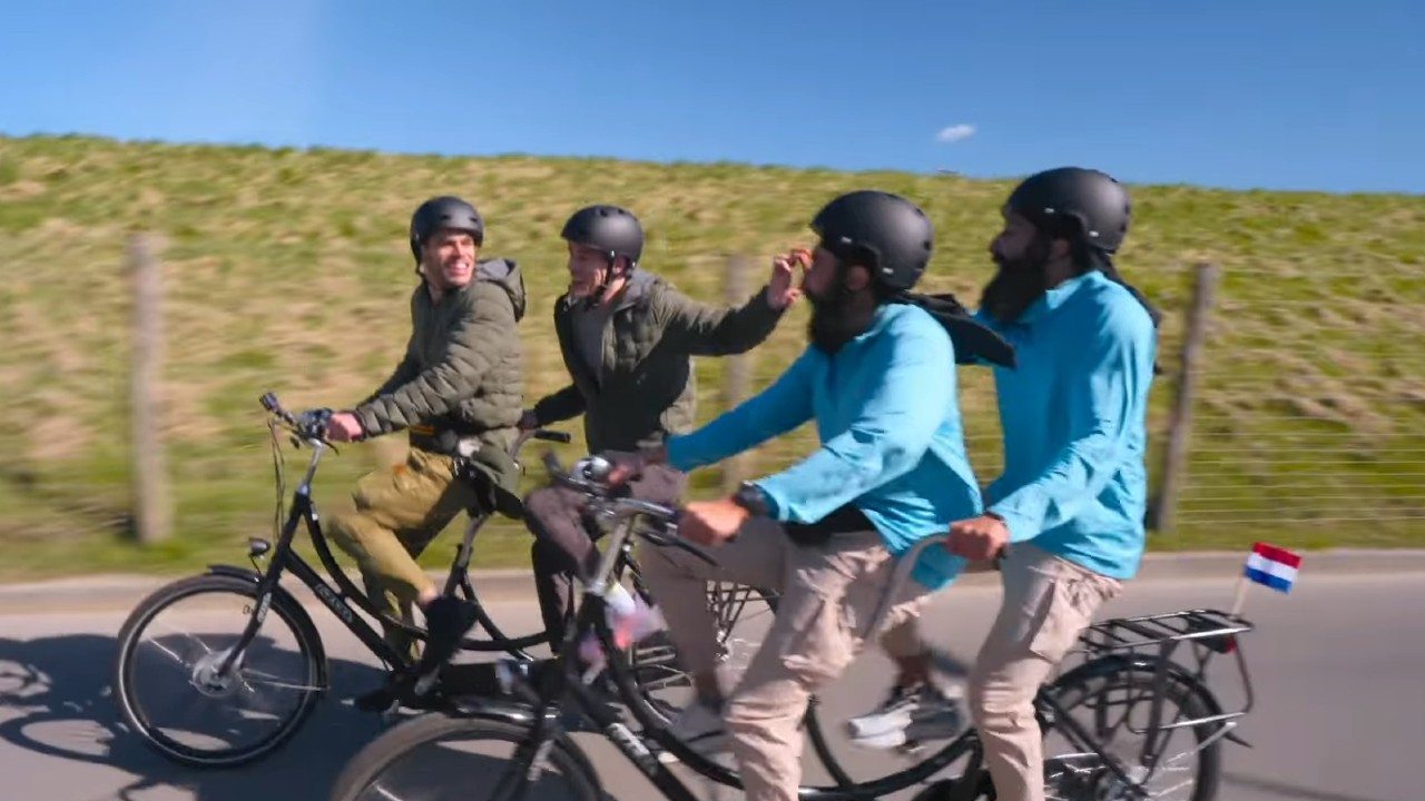 Eric Des Lauriers and Tucker Des Lauriers ride on a bike next to Jag Bains and Jas Bains in The Amazing Race.