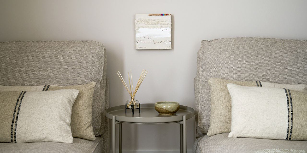 A sensory nook with two beige chairs, white cushions and a grey coffee table. There is a reed diffuser on top of the coffee table