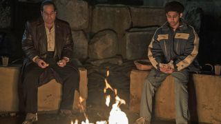 Oz Cobb and Victor Aguilar eating sandwiches while sitting by a campfire in The Penguin