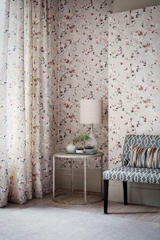 Floris wallpaper in Spring Rose from Romo with round table and cream lampshade light in alcove with grey geometric patterned bench
