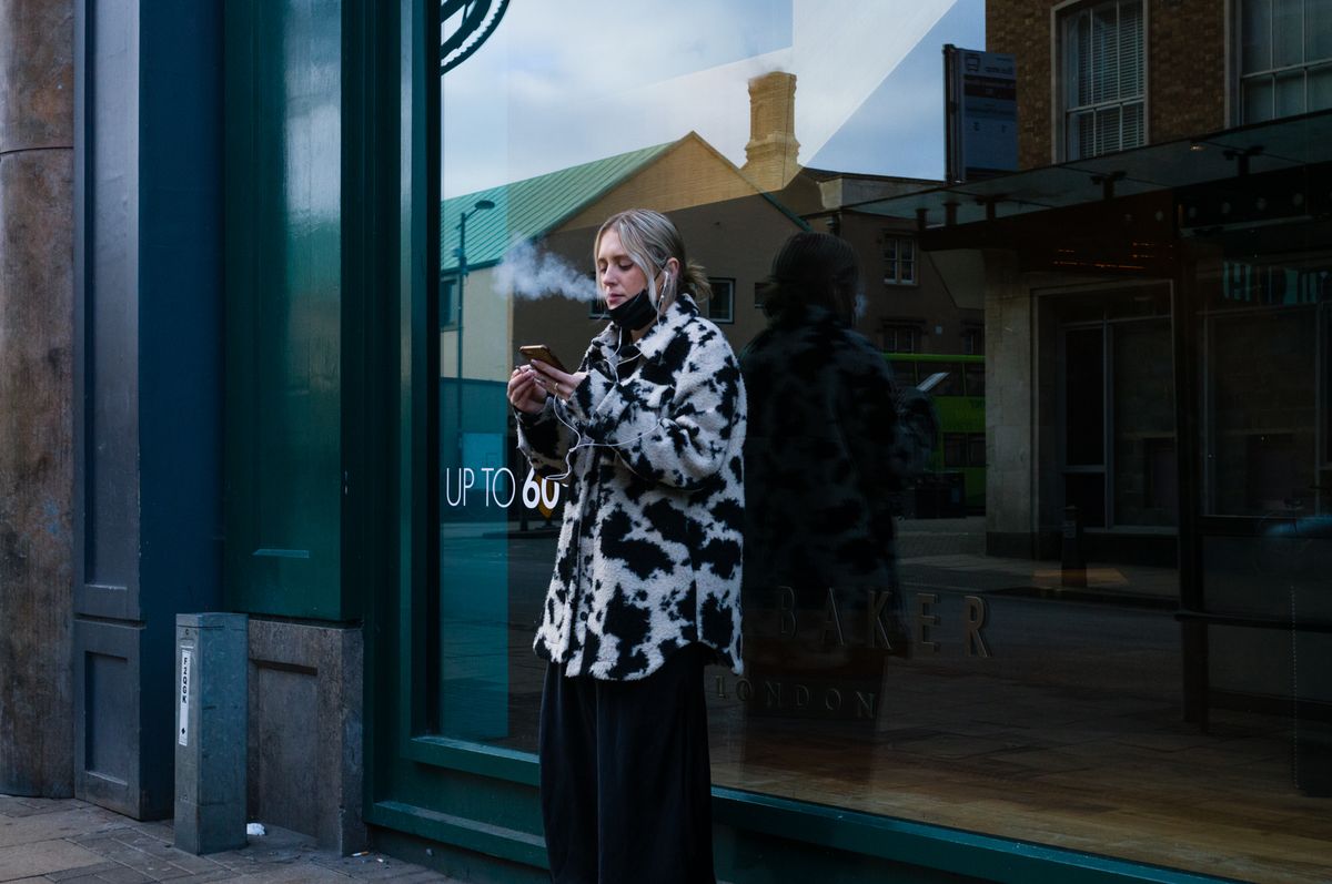 A person smoking in front of a window